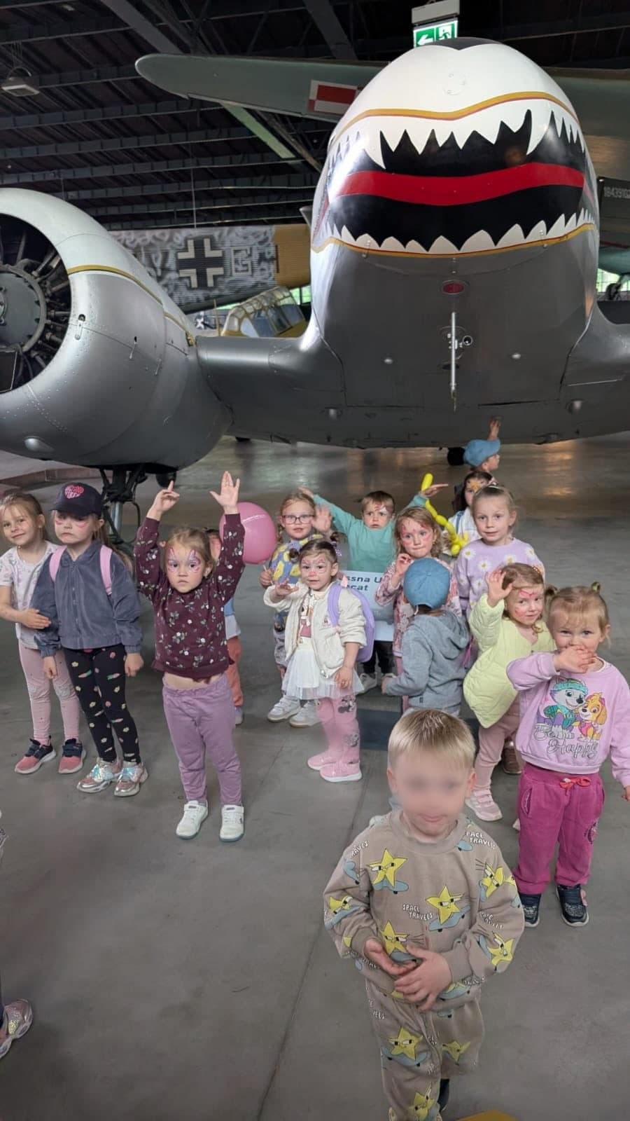 Dzieci w hangarze muzeum lotnictwa przy malowanym samolocie