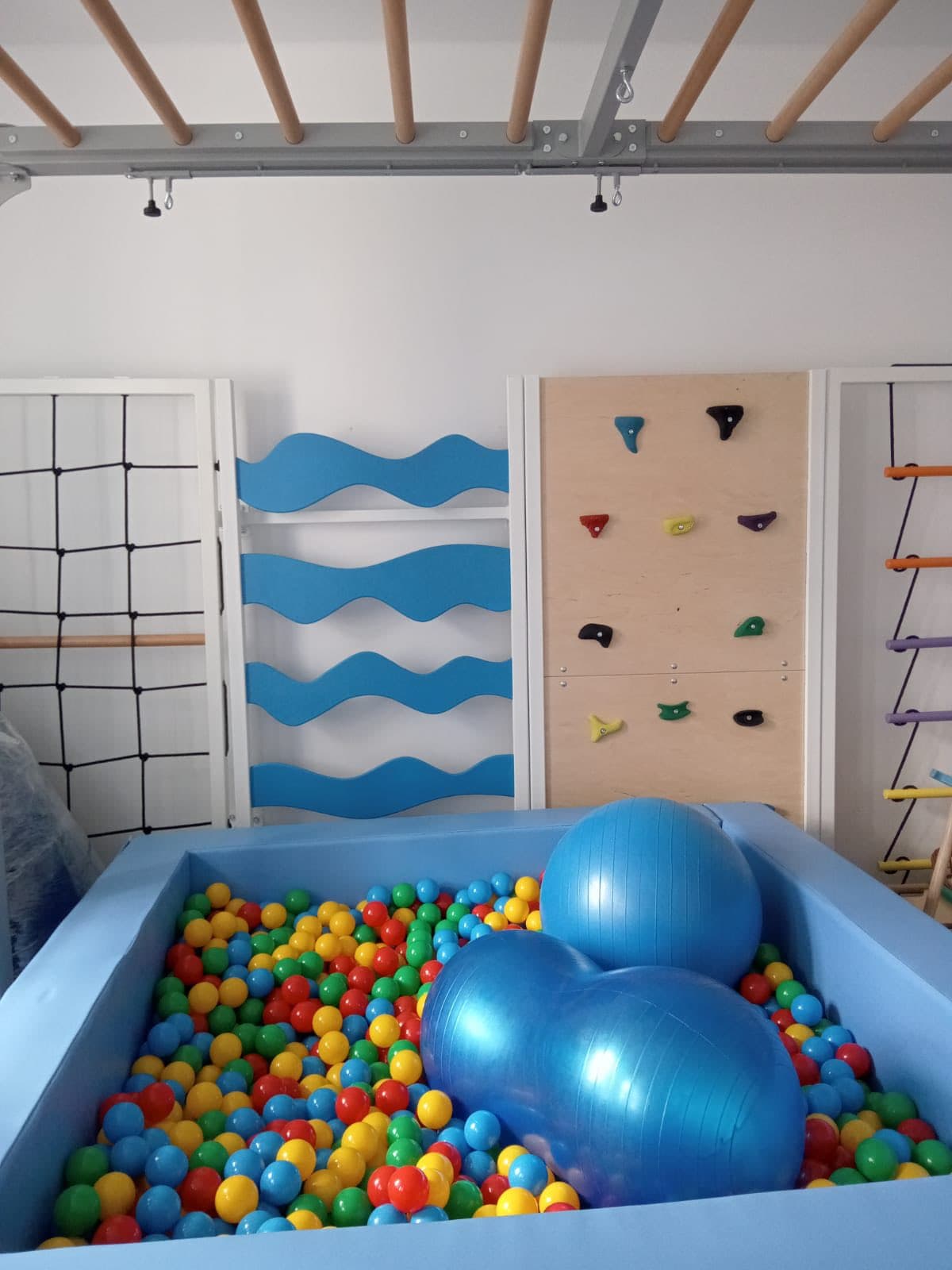 Sala integracji sensorycznej — basen kulkowy z piłkami gimnastycznymi i sprzętem wspinaczkowym